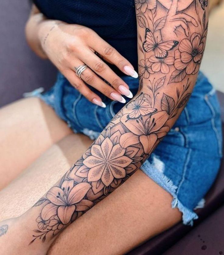 a woman sitting on top of a couch with her arm covered in tattoos and flowers