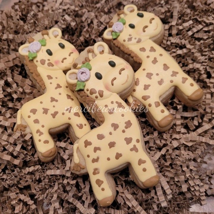 decorated cookies in the shape of giraffes on top of some wood chips