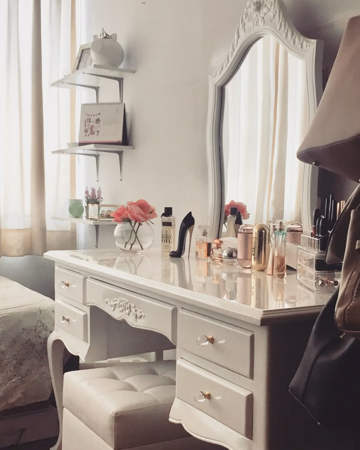 a white desk topped with lots of drawers next to a mirror and chair in a room