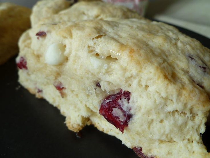 two scones sitting on top of a plate next to each other with cranberry toppings