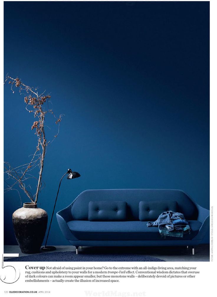 a blue couch sitting next to a vase with a plant in it on top of a table