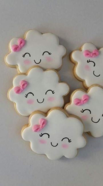 four decorated cookies in the shape of clouds with pink bows on their ears and eyes