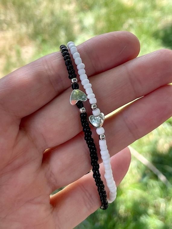 a person holding two different bracelets in their hand, one is white and the other is black