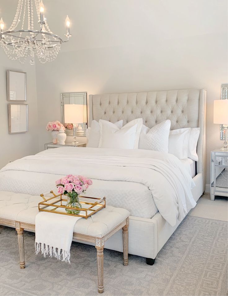 a white bedroom with a chandelier and bed