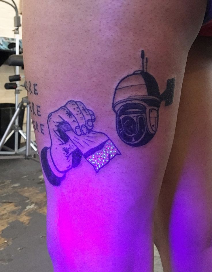 a woman's leg with tattoos on it and a purple light in the background