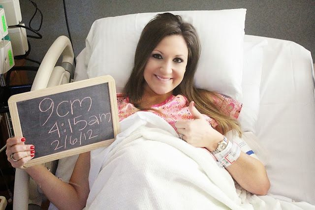 a woman laying in a hospital bed holding a sign