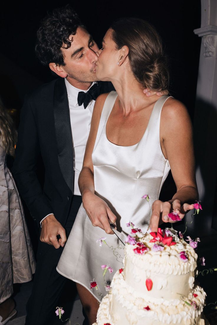 a bride and groom are kissing while cutting their wedding cake at the end of the night