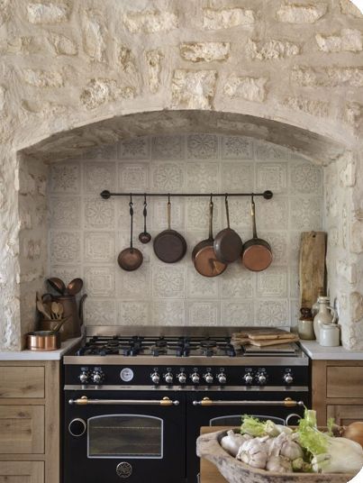 a kitchen with an oven, stove and pots on the wall in front of it