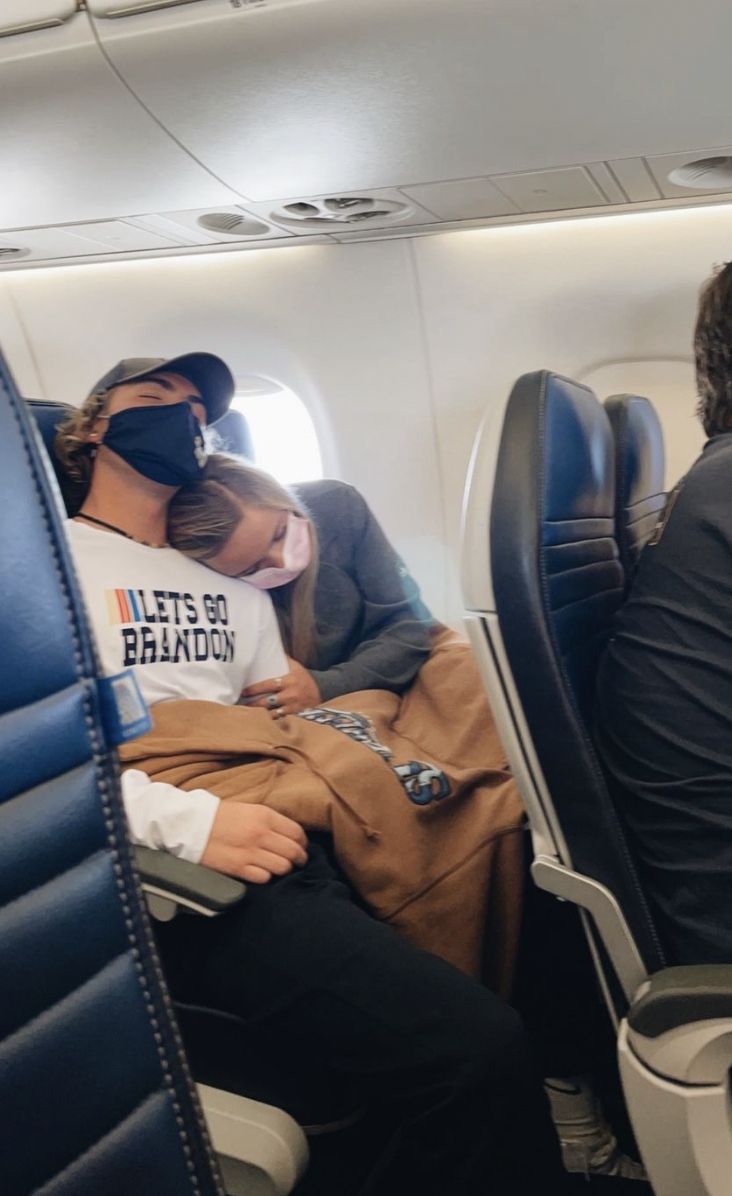 two people sitting on an airplane with their backs to each other, wearing blindfolds