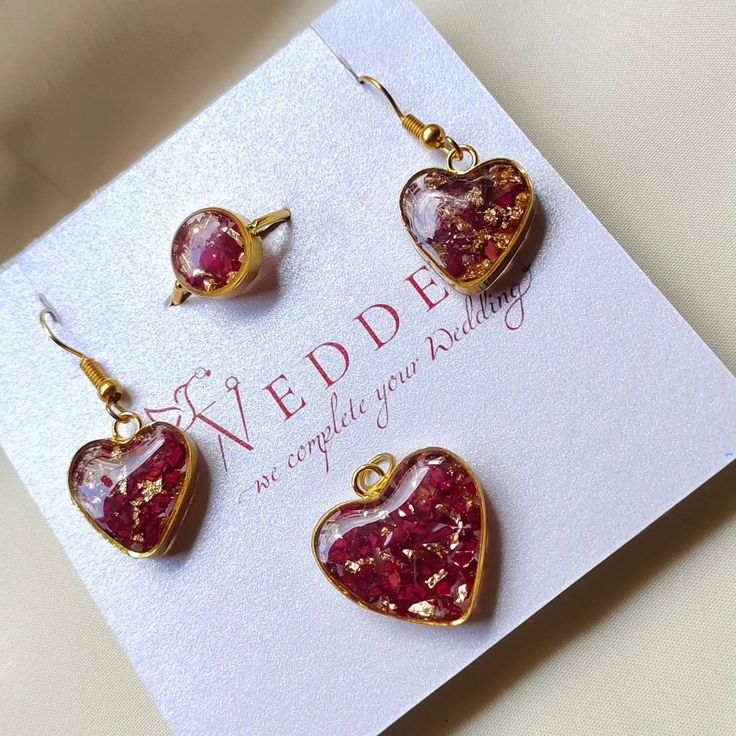 three red heart shaped earrings on top of a card with the words wedder written in gold