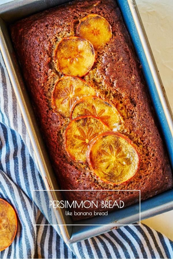 a loaf of bread with sliced oranges on top in a blue baking pan next to two slices of fruit