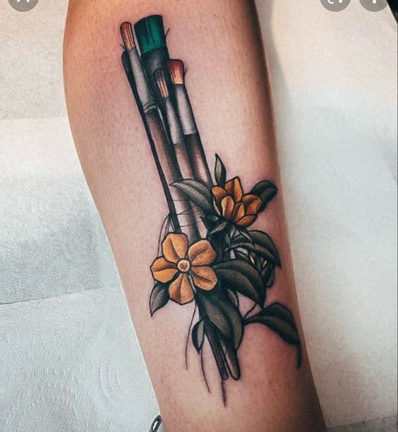 a woman's leg with some flowers on it and two pencils in the middle