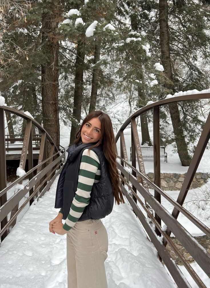 a woman standing on a bridge in the snow