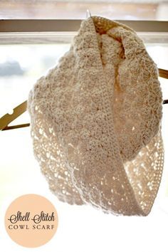 a white crocheted shawl hanging from a window sill with the words shell stitch cowl scarf on it