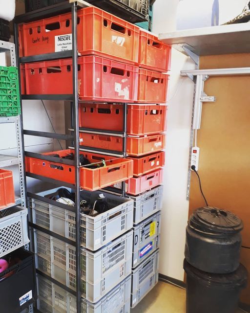 the shelves are full of orange and gray containers with lids on them, along with other storage bins