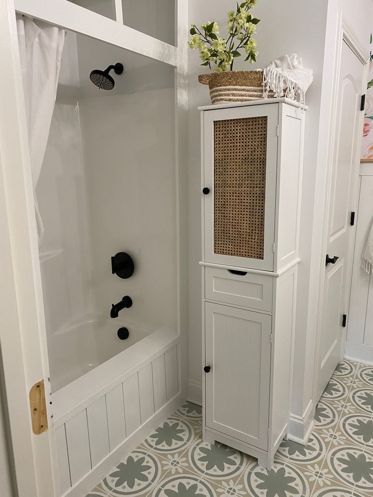 a bathroom with a white cabinet next to a bath tub