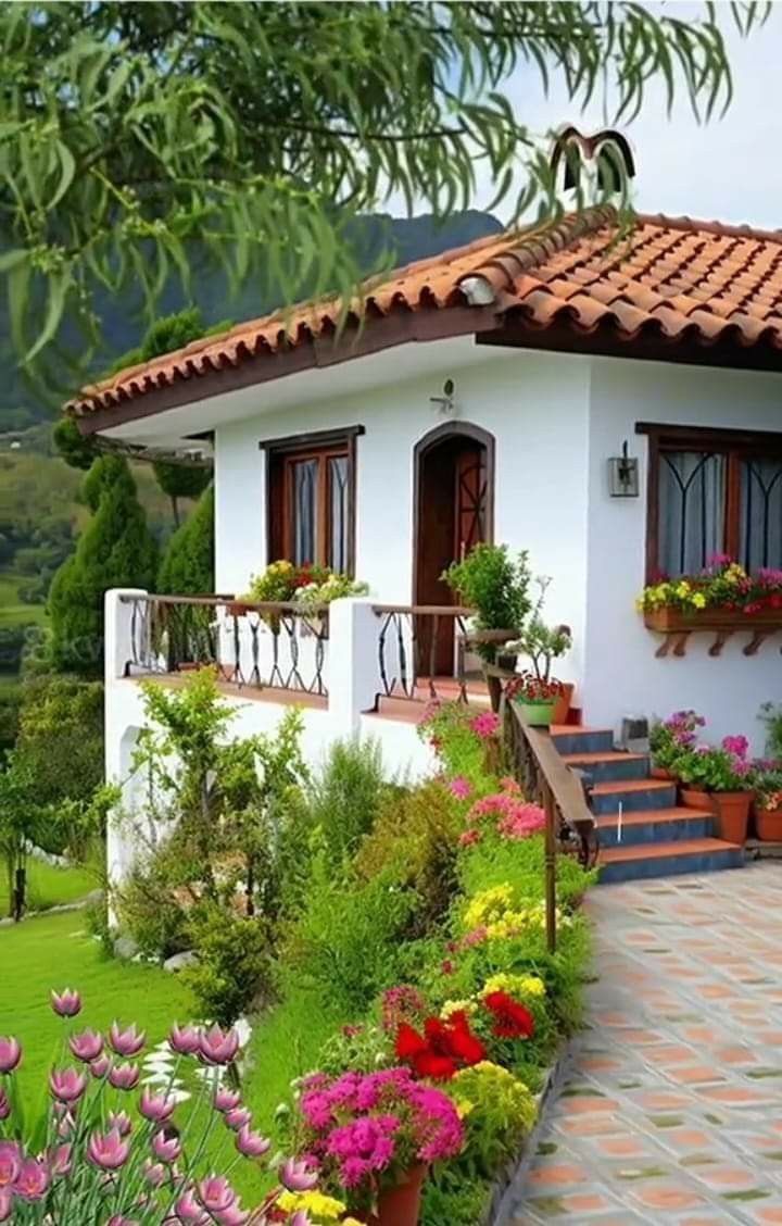 a white house with flowers in the front yard and stairs leading up to it's second story