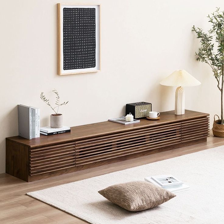 a living room with a large wooden shelf next to a lamp and a plant on the floor