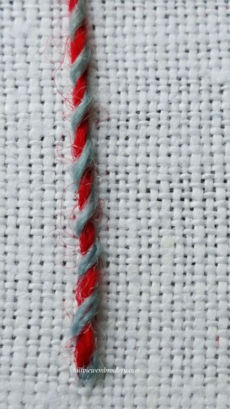 a close up of a red and white striped piece of fabric with yarn on it