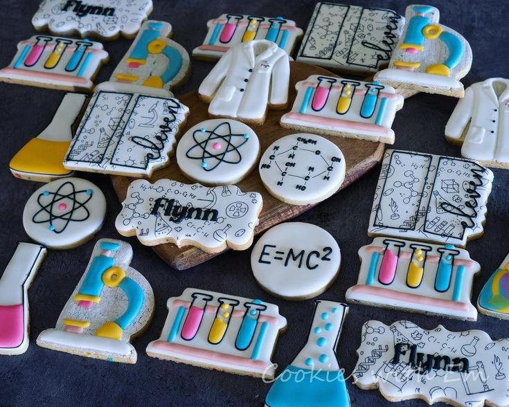 decorated cookies are arranged on a table with writing and science themed items in the shape of lab equipment