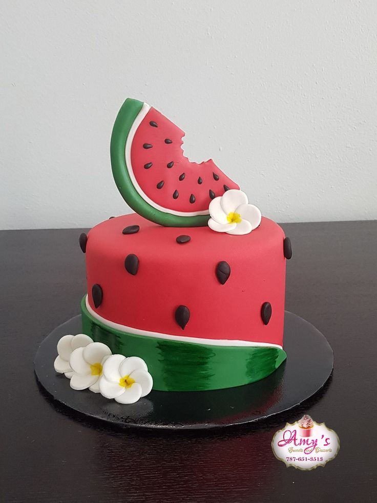 a watermelon cake with black dots and white flowers