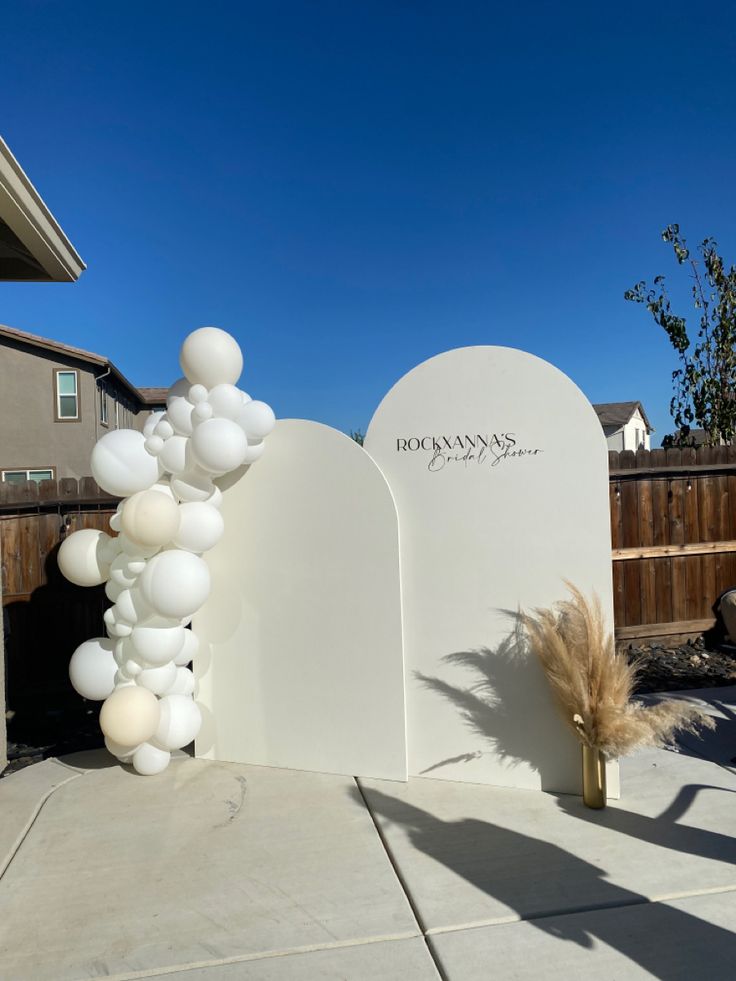 an arch is decorated with white balloons and some pamodia in front of it