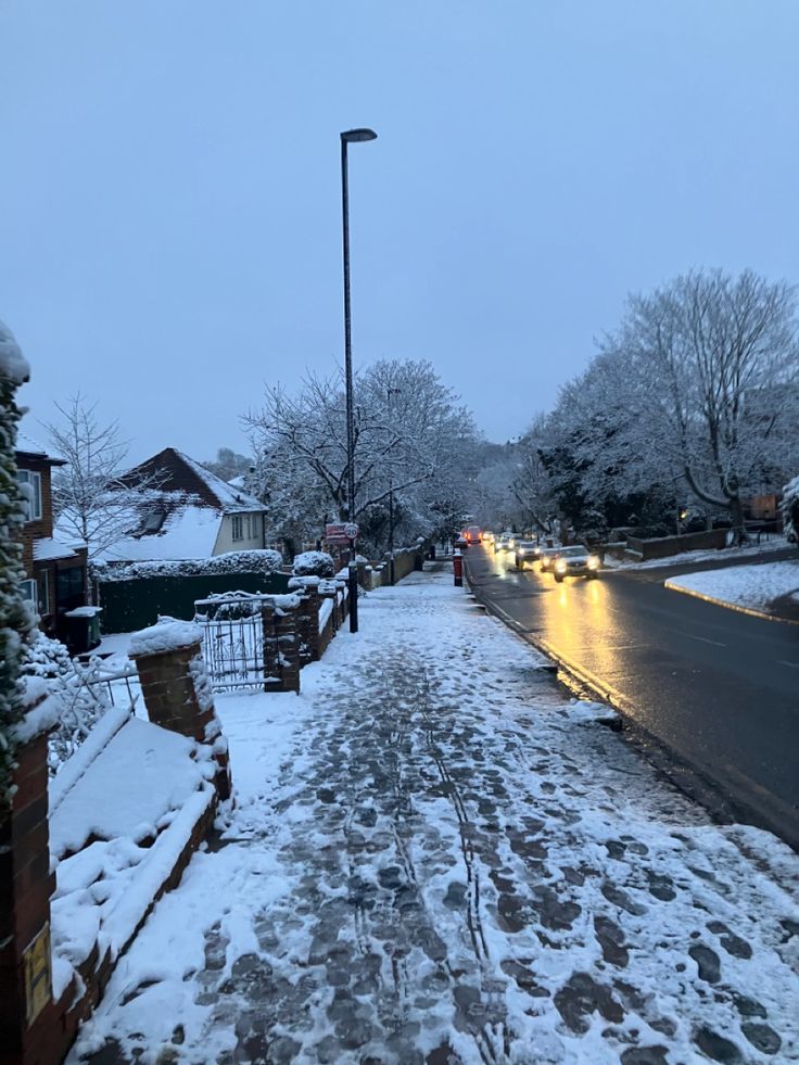 a snowy street with cars parked on the side