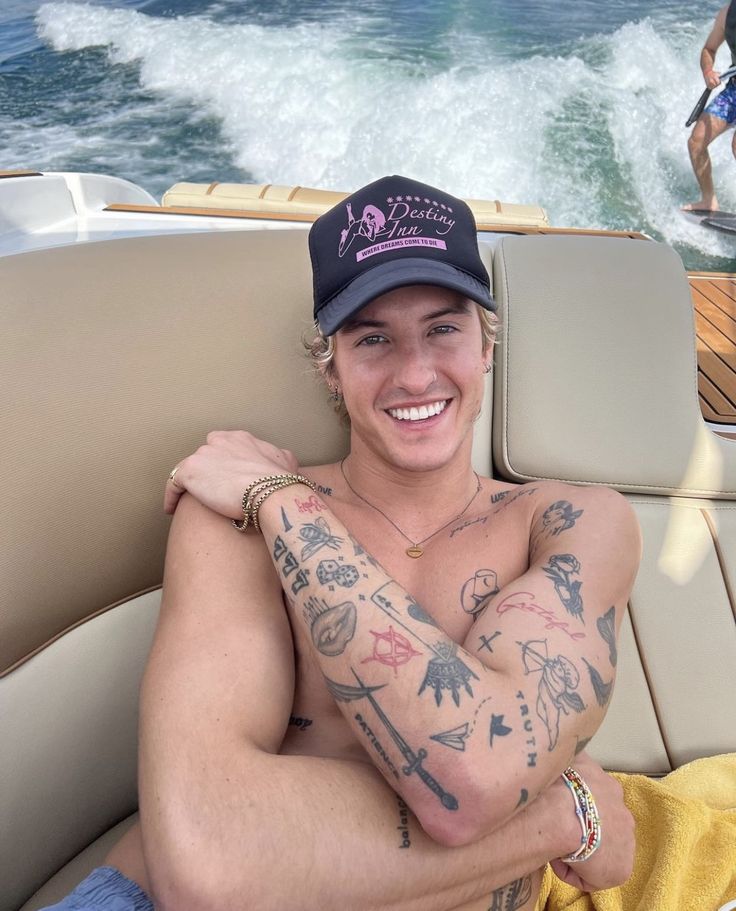 a man with tattoos on his arm sitting in a boat