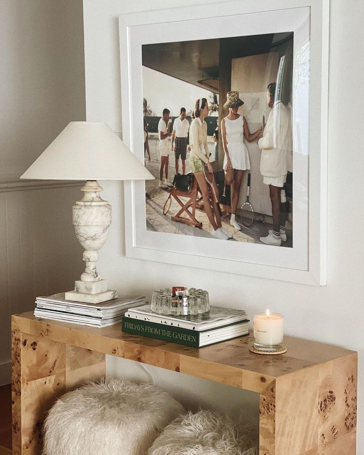 a table with some books on it and a lamp in front of the picture above it