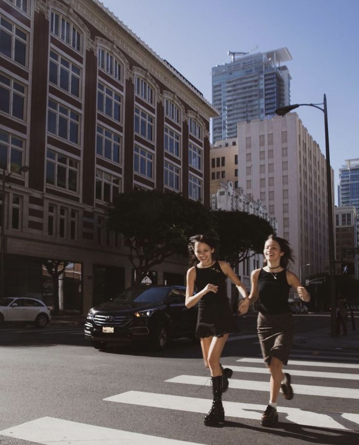 two young women running across a crosswalk in the city