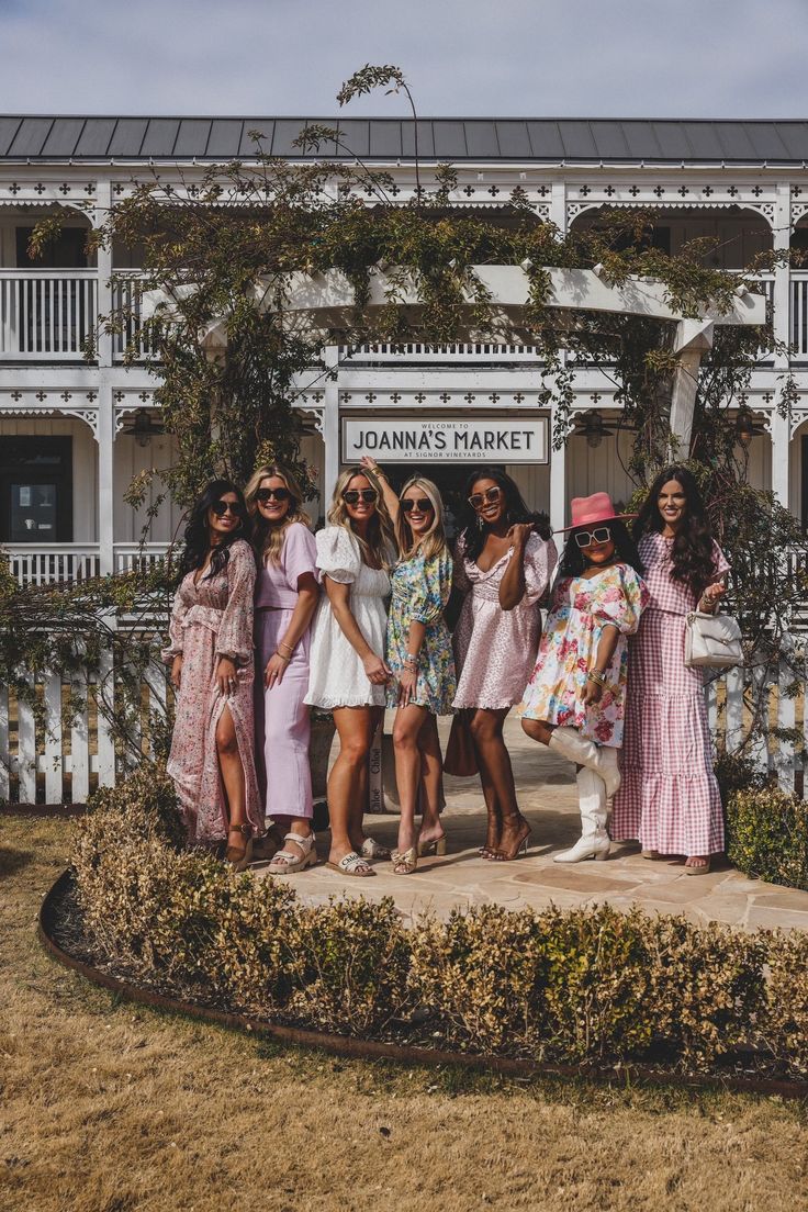 a group of women standing next to each other in front of a building