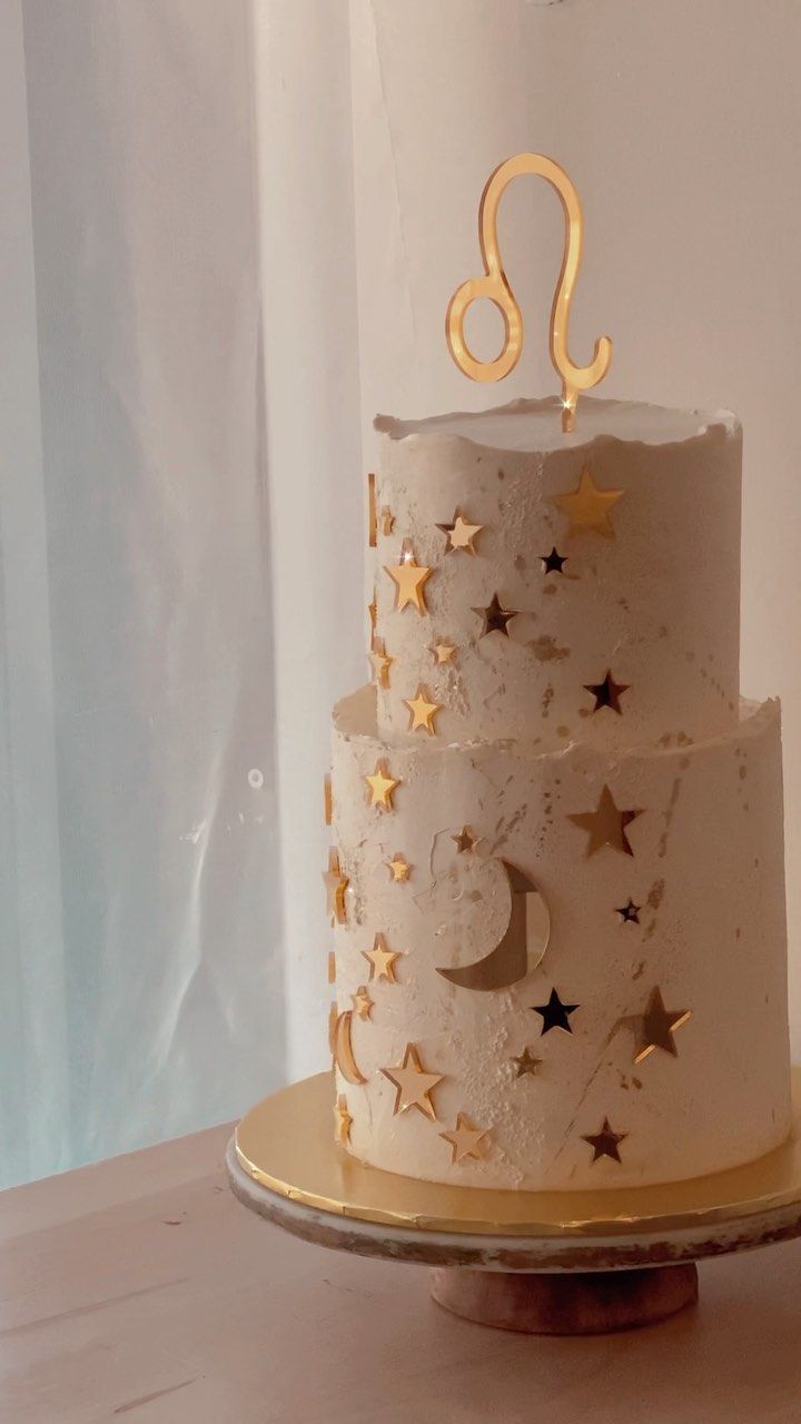 a three tiered cake with gold stars and a number on top is sitting on a table