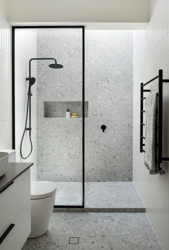 a bathroom with a walk in shower next to a white toilet and black accents on the walls