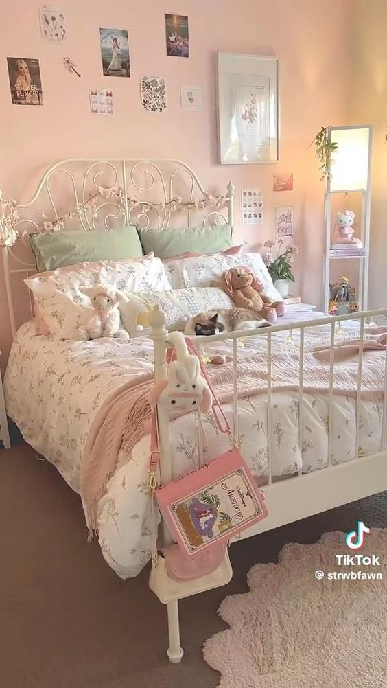 a white bed sitting in a bedroom next to a pink wall with pictures on it