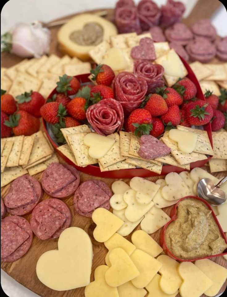 an assortment of cheeses, crackers, and strawberries on a platter