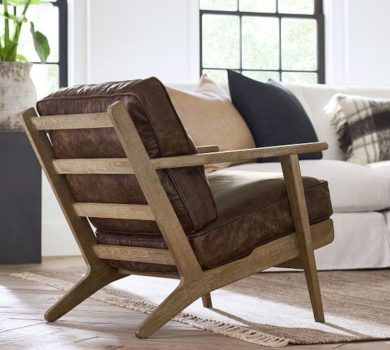 a brown leather chair sitting on top of a wooden floor next to a white couch