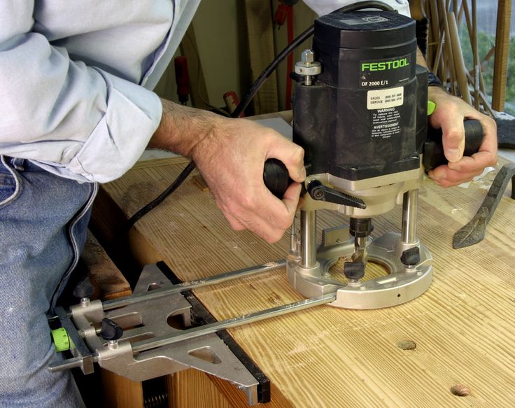 a man using a router on a wooden table