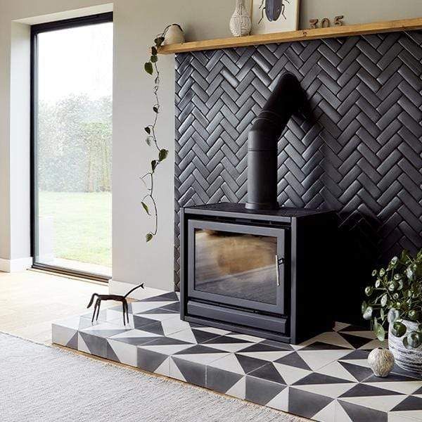 a living room with a black and white checkered tile floor, wood burning stove and potted plants