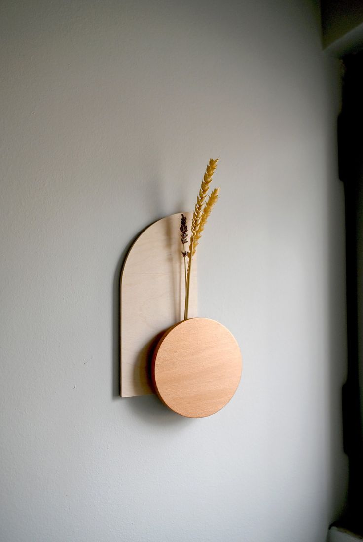 a wooden clock mounted to the side of a wall with a plant in it's center