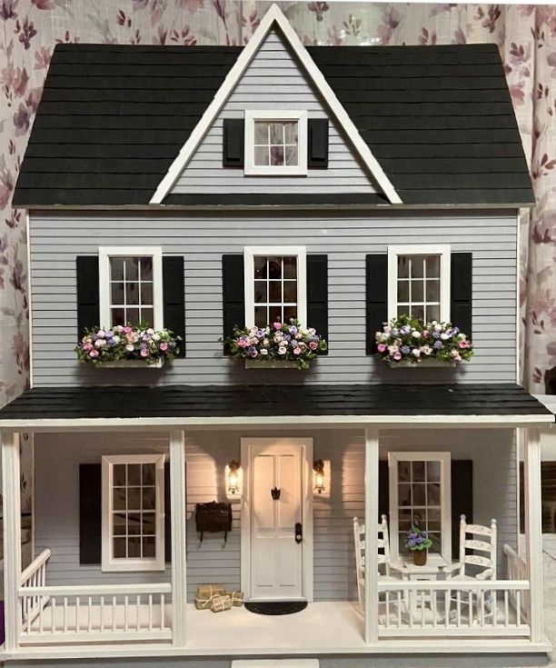 a doll house with flowers in the window boxes on the front and side of it