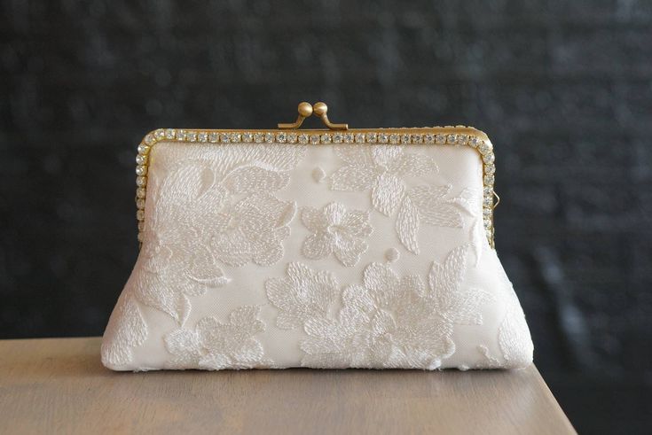 a white clutch bag sitting on top of a wooden table next to a black wall