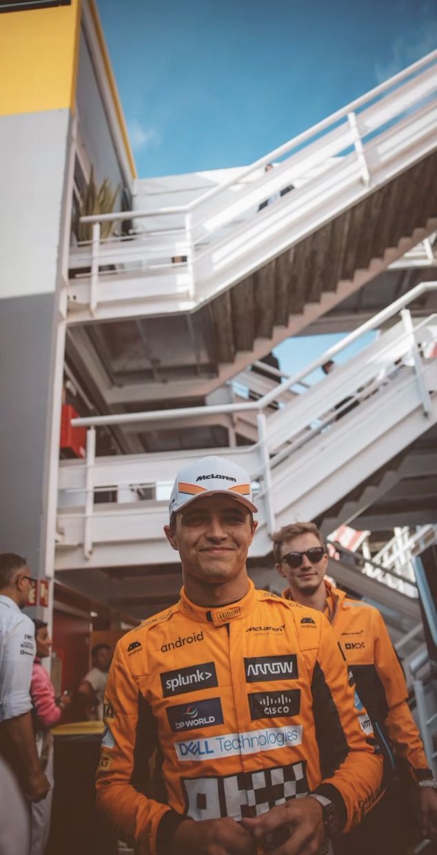 a man in an orange racing suit standing next to some stairs