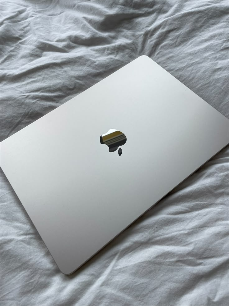 an apple laptop computer sitting on top of a bed