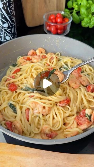 a bowl full of pasta with shrimp and tomatoes