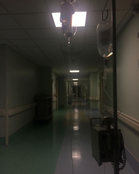 an empty hospital hallway with lights on the ceiling