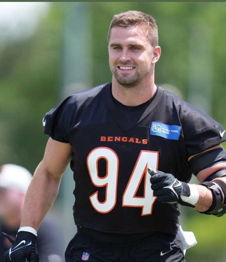 a football player is smiling and holding his gloves