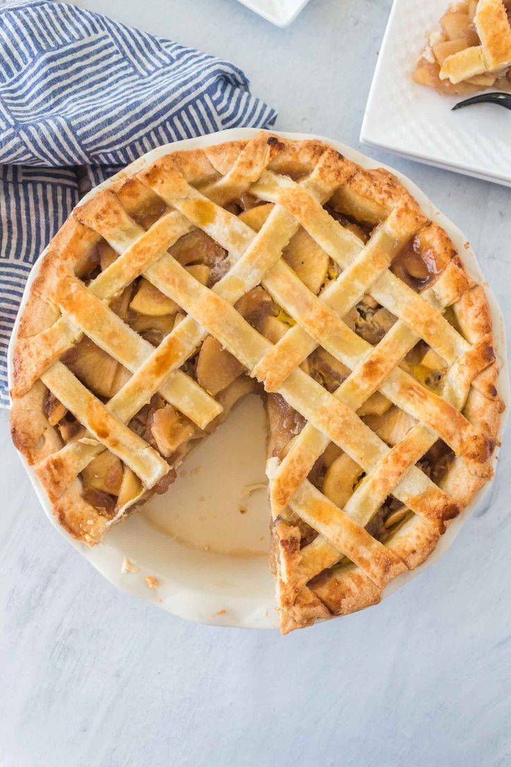 a pie on a plate with one slice cut out and the whole pie in the background