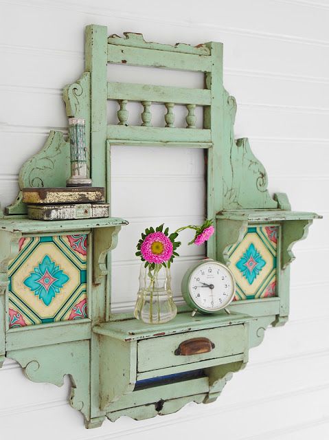 an old green shelf with a clock and vase on it next to a white wall