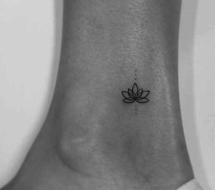 a black and white photo of a lotus flower tattoo on the side of a woman's ankle