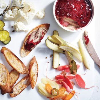 an assortment of food including bread, vegetables and fruit on a white plate with a knife